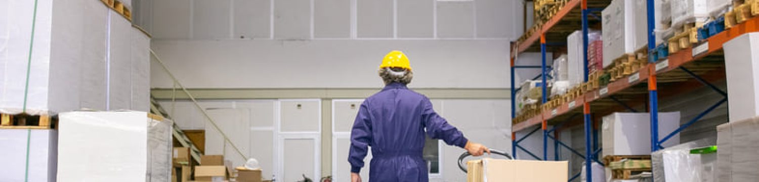 senior-logistic-worker-hardhat-uniform-walking-warehouse-wheeling-palette-jack-back-view-full-length-labor-logistics-concept